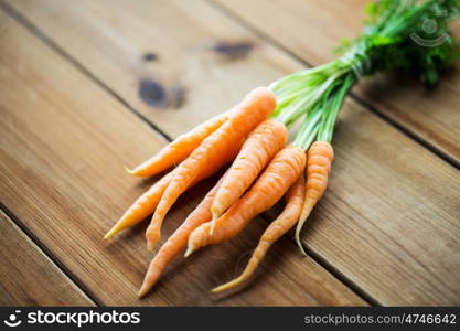 healthy eating, food, dieting and vegetarian concept - close up of carrot bunch on wooden table