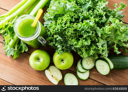 healthy eating, food, dieting and vegetarian concept - close up of glass jug with green juice, fruits and vegetables on wooden table
