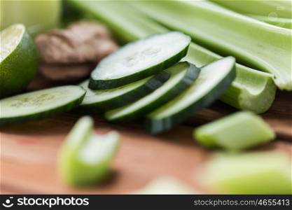 healthy eating, food, dieting and vegetarian concept - close up of green celery stems and sliced cucumber on wood