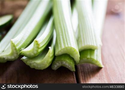 healthy eating, food, dieting and vegetarian concept - close up of green celery stems on wood