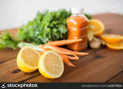 healthy eating, food, dieting and vegetarian concept - close up of lemon and bottle with carrot juice, fruits and vegetables on wooden table