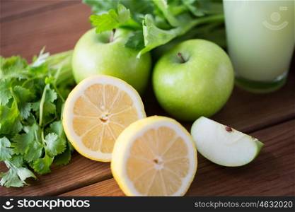 healthy eating, food, dieting and vegetarian concept - close up of lemons with apples, celery and green juice on wooden table