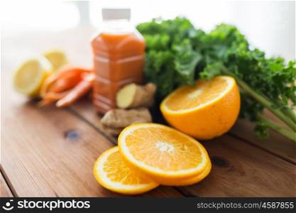 healthy eating, food, dieting and vegetarian concept - close up of orange and bottle with carrot juice, fruits and vegetables on wooden table