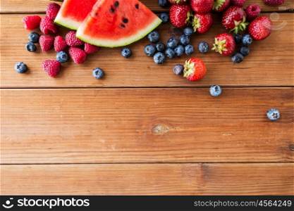 healthy eating, food, dieting and vegetarian concept - close up of raspberry with strawberry, blackberry and watermelon slices on wooden table