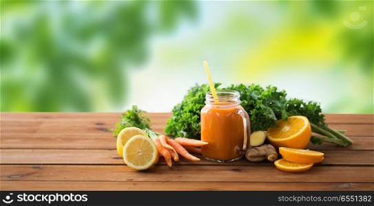 healthy eating, food, dieting and vegetarian concept - glass jug of carrot juice, fruits and vegetables on wooden table over green natural background. glass jug of carrot juice, fruits and vegetables. glass jug of carrot juice, fruits and vegetables