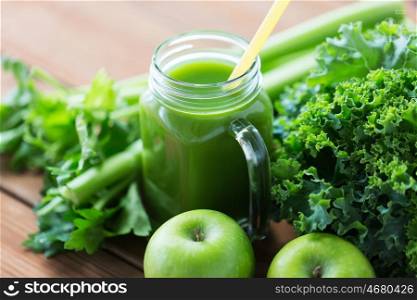 healthy eating, food, dieting and vegetarian concept - glass jug or mug with green juice, fruits and vegetables on wooden table