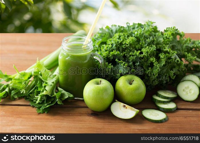 healthy eating, food, dieting and vegetarian concept - glass mug or mason jar with green juice, fruits and vegetables on wooden table over natural background. mason jar with green juice and vegetables. mason jar with green juice and vegetables
