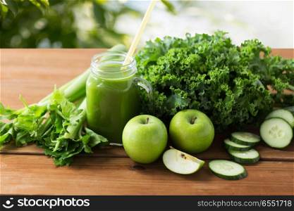 healthy eating, food, dieting and vegetarian concept - glass mug or mason jar with green juice, fruits and vegetables on wooden table over natural background. mason jar with green juice and vegetables. mason jar with green juice and vegetables