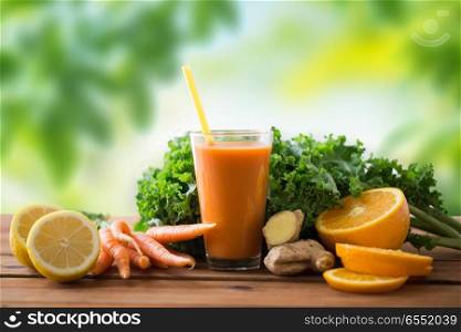healthy eating, food, dieting and vegetarian concept - glass of carrot juice, fruits and vegetables on wooden table over green natural background. glass of carrot juice, fruits and vegetables. glass of carrot juice, fruits and vegetables