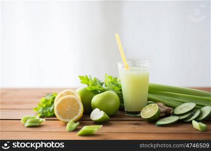 healthy eating, food, dieting and vegetarian concept - glass of green juice with fruits and vegetables on wooden table