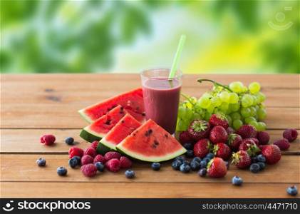 healthy eating, food, dieting and vegetarian concept - glass with fruit and berry juice or smoothie on wooden table over green natural background. fruit and berry juice or smoothie on wooden table. fruit and berry juice or smoothie on wooden table