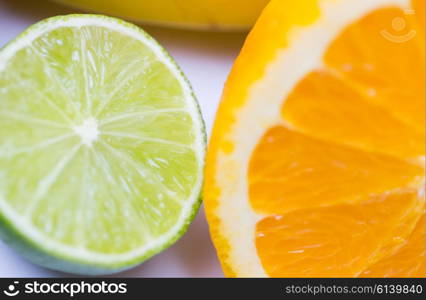 healthy eating, food, fruits and diet concept - close up of fresh juicy orange and lime