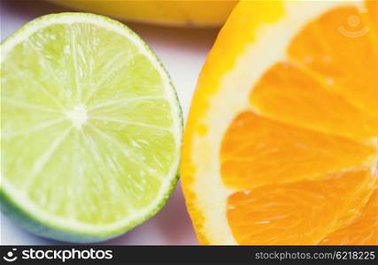 healthy eating, food, fruits and diet concept - close up of fresh juicy orange and lime