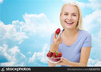 healthy eating, food, fruits, diet and people concept - happy woman eating strawberry over blue sky and clouds background