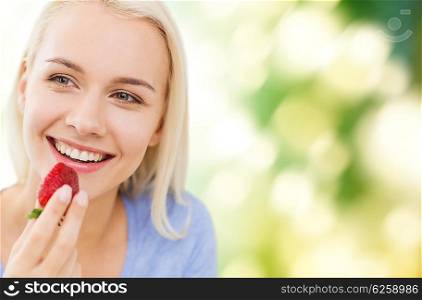 healthy eating, food, fruits, diet and people concept - happy woman eating strawberry over green natural background