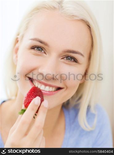 healthy eating, food, fruits, diet and people concept - happy woman eating strawberry at home