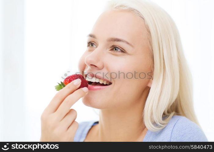 healthy eating, food, fruits, diet and people concept - happy woman eating strawberry at home