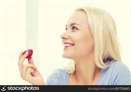 healthy eating, food, fruits, diet and people concept - happy woman eating strawberry at home