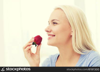 healthy eating, food, fruits, diet and people concept - happy woman eating strawberry at home