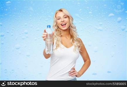 healthy eating, hydration, diet and people concept - happy beautiful young woman holding bottle of water over blue wet background. happy beautiful young woman with bottle of water