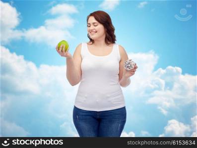 healthy eating, junk food, diet and choice people concept - smiling plus size woman choosing between apple and donut over blue sky and clouds background