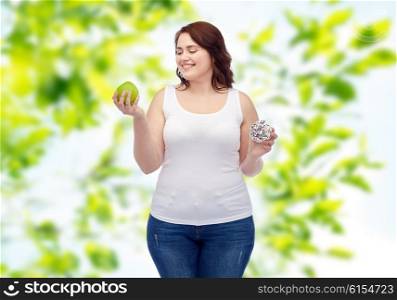 healthy eating, junk food, diet and choice people concept - smiling plus size woman choosing between apple and donut over green natural background