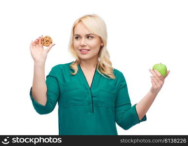 healthy eating, junk food, diet and choice people concept - smiling woman choosing between apple and cookie