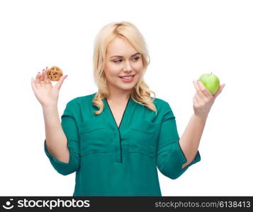 healthy eating, junk food, diet and choice people concept - smiling woman choosing between apple and cookie