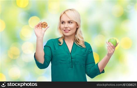 healthy eating, junk food, diet and choice people concept - smiling woman choosing between apple and cookie over green lights background