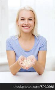 healthy eating, medicine, health care, food supplements and people concept - happy woman holding pills or capsules at home