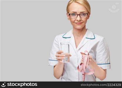 Healthy eating or lifestyle concept - female woman doctor holding and a glass of clear fresh water and measure tape.. Healthy eating or lifestyle concept - female woman doctor holding and a glass of clear fresh water and measure tape