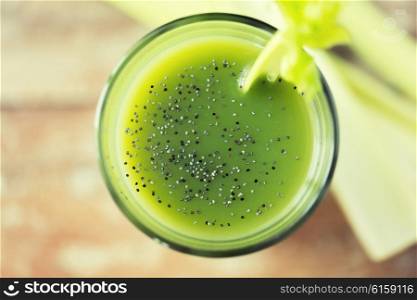 healthy eating, organic food and diet concept - close up of fresh green juice with chia seeds and celery on table