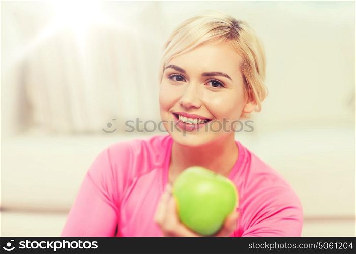 healthy eating, organic food, diet and people concept - happy woman eating green apple at home. happy woman eating green apple at home