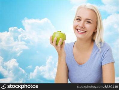 healthy eating, organic food, fruits, diet and people concept - happy woman eating green apple over blue sky and clouds background