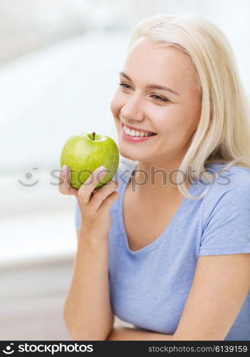 healthy eating, organic food, fruits, diet and people concept - happy woman eating green apple at home