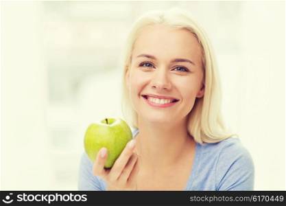 healthy eating, organic food, fruits, diet and people concept - happy woman eating green apple at home