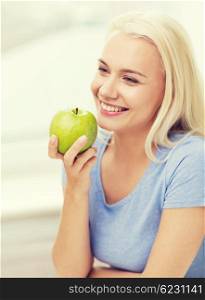 healthy eating, organic food, fruits, diet and people concept - happy woman eating green apple at home