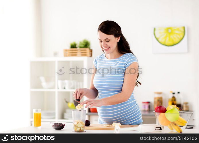 healthy eating, pregnancy and people concept - pregnant woman with knife putting fruits to blender cup at home kitchen. pregnant woman putting fruits to blender at home