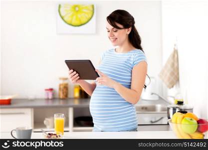 healthy eating, pregnancy and people concept - pregnant woman with tablet pc computer having breakfast at home kitchen. pregnant woman with tablet pc eating at home