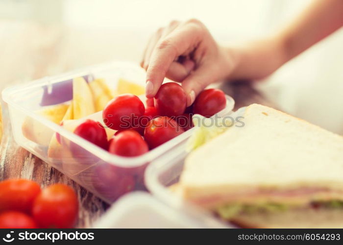 healthy eating, storage, dieting and people concept - close up of woman with food in plastic container at home kitchen