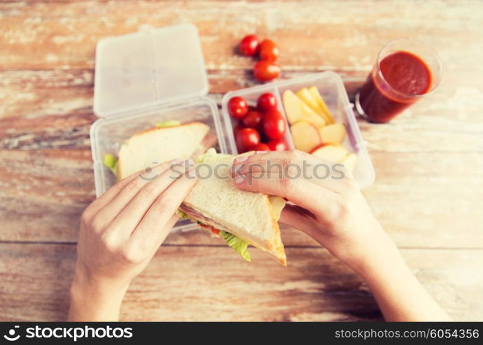 healthy eating, storage, dieting and people concept - close up of woman hands with food in plastic container at home kitchen