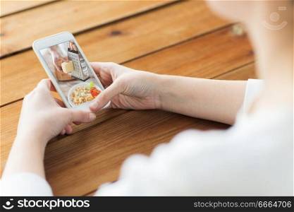 healthy eating, technology and food concept - close up of woman watching tutorial cooking video on smartphone. close up of woman with cooking video on smartphone