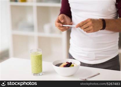 healthy eating, technology and people concept - man with smartphone having breakfast at home kitchen. man with smartphone having breakfast at home