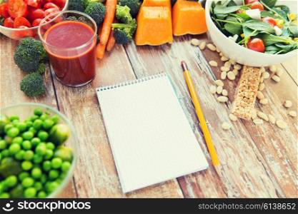healthy eating, vegetarian food, advertisement and culinary concept - close up of ripe vegetables and notebook with pencil on wooden table