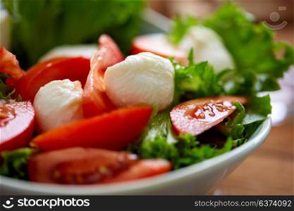 healthy eating, vegetarian food and culinary concept - close up of vegetable salad with tomatoes and mozzarella cheese. close up of vegetable salad with mozzarella