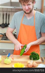 Healthy eating, vegetarian food, cooking, dieting and people concept. Closeup male hands in kitchen preparing fresh vegetables salad peeling cucumber