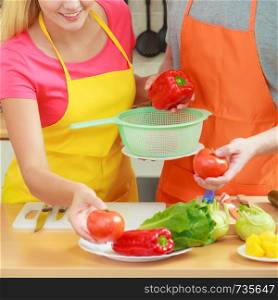 Healthy eating, vegetarian food, cooking, dieting and people concept Happy young couple woman and man having fun in kitchen at home preparing fresh vegetables salad