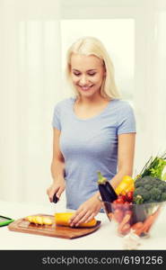 healthy eating, vegetarian food, cooking , dieting and people concept - smiling young woman chopping vegetables at home