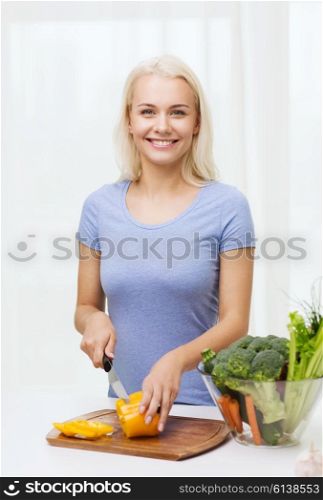 healthy eating, vegetarian food, cooking, dieting and people concept - smiling young woman chopping vegetables at home