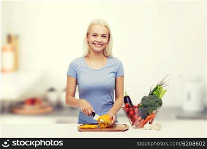 healthy eating, vegetarian food, cooking, dieting and people concept - smiling young woman chopping vegetables over kitchen background
